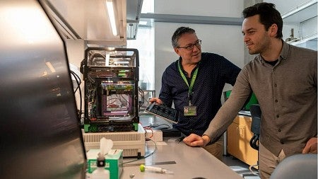 Two white, male scientists, Paul Dalton and Ievgenii Liashenko working with a 3D printer in the lab